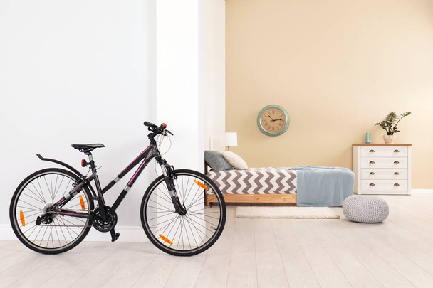 Bicycle near light wall in stylish room interior - Zdjęcie, obraz