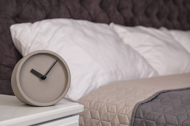 Stylish alarm clock on nightstand in bedroom. Space for text - Fotó, kép