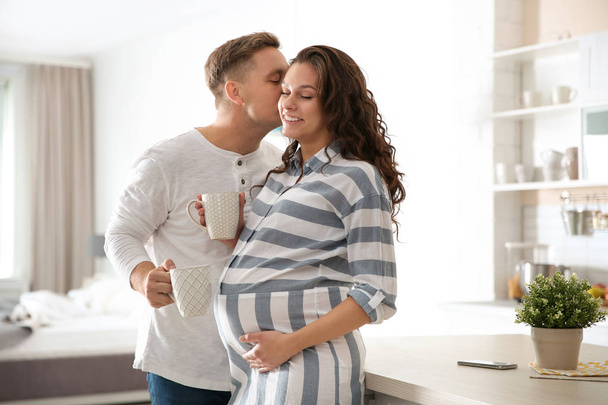 Беременная женщина с мужем на кухне. Счастливая молодая семья
 - Фото, изображение