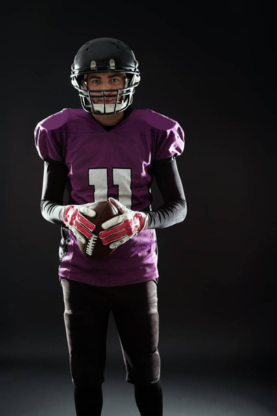 American football player with ball on dark background - Foto, imagen