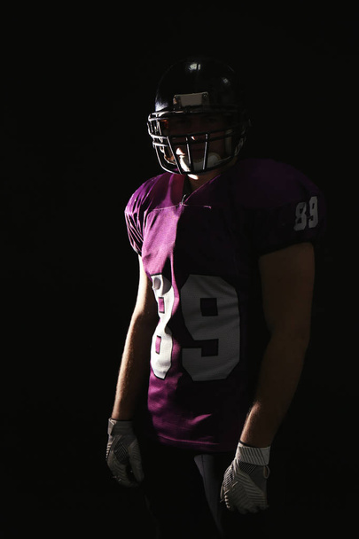 American football player wearing uniform on dark background - Fotó, kép