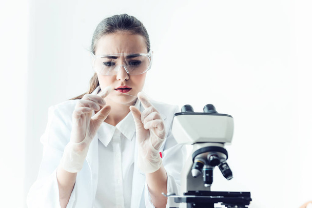 Retrato de una joven investigadora científica está analizando los resultados a través del microscopio en la sala de laboratorio de investigación
. - Foto, imagen