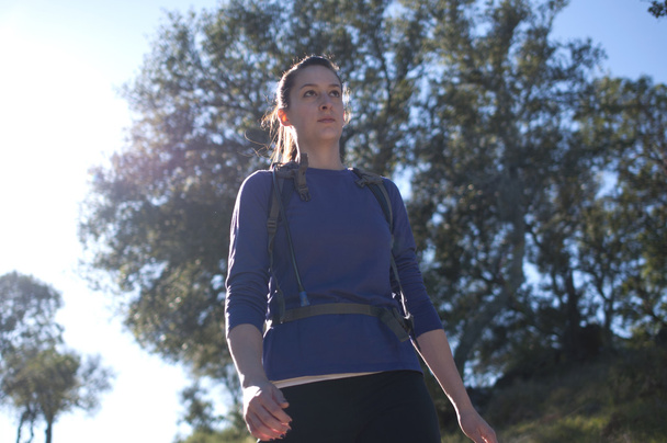 Frontal centered close up of woman hiking in blue shirt facing right - Photo, Image