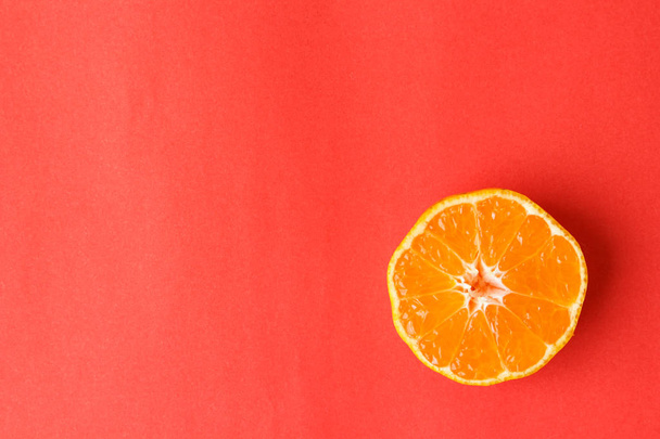 赤の背景にオレンジ色の果物の皮 - 写真・画像