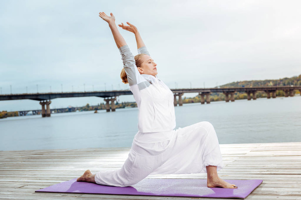 Young woman doing stretching exercises outdoor near the water - Photo, Image