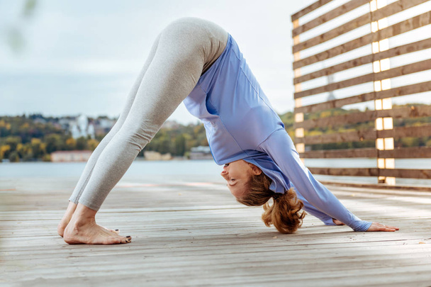 Woman concentratedly practising Downward-Facing Dog yoga pose - Photo, image