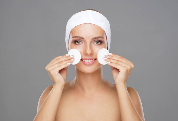 Mujer joven limpiándose la cara con una almohadilla de algodón. Niña quitando cosméticos con discos higiénicos. Concepto de cosmetología
. - Foto, imagen