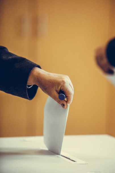 Kleurenbeeld van een persoon die een stem uitbrengt bij een stembureau, tijdens verkiezingen. - Foto, afbeelding