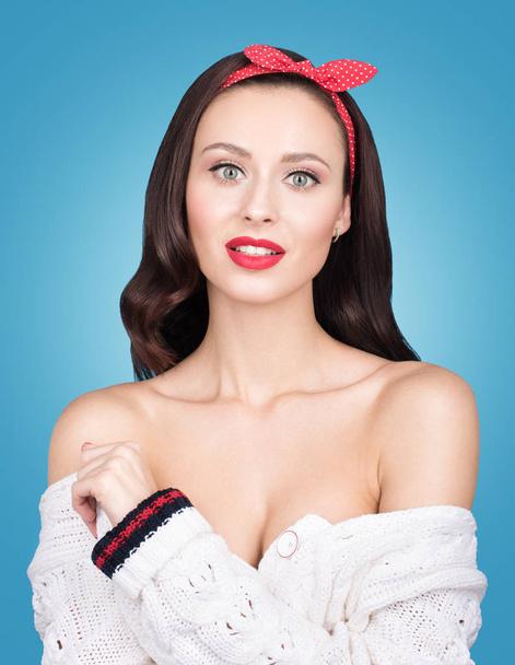 Barevný portrét beauty Studio krásná mladá žena izolována na modrém pozadí. Světlý make-up a stylový vzhled. Bílý pletený svetr, holá ramena a červená čelenka ve vlasech - Fotografie, Obrázek