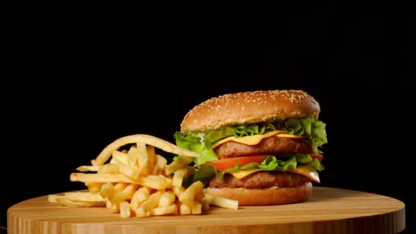 Burger wołowy rzemiosła i frytki, sos na białym na czarnym tle. Fast food - Materiał filmowy, wideo