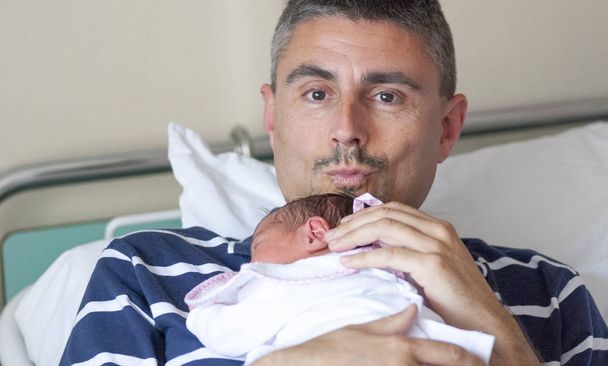Feliz padre besando a su hija en la guardería del hospital. Primer día de vida, concepto de nacimiento. - Foto, Imagen