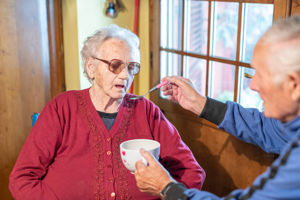 Anciano alimentando a su esposa en casa, se centran en la mujer
. - Foto, Imagen