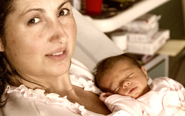 Madre feliz sosteniendo al bebé recién nacido en brazos en el hospital. Primeros días de vida
. - Foto, Imagen