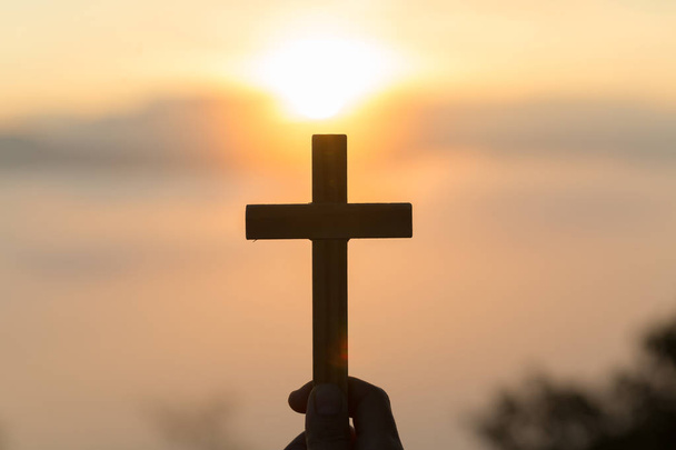 Silhouette de jeunes mains humaines priant avec une croix au lever du soleil, religion chrétienne concept arrière-plan
. - Photo, image