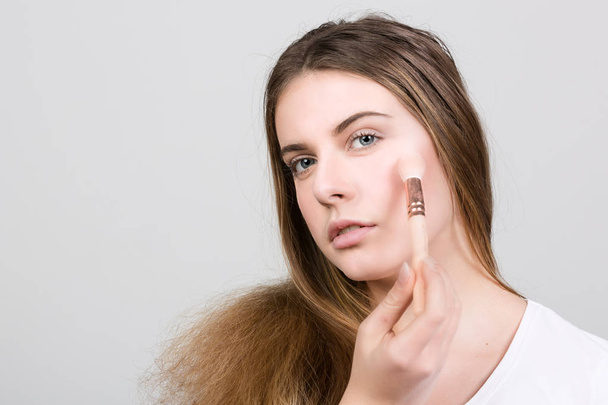 teenager is applying powder for make up - Photo, Image
