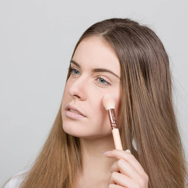 vrouwelijke tiener is het toepassen van poeder voor make up - Foto, afbeelding