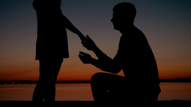 Silhouette di un uomo si siede sul ginocchio e mette l'anello sulla mano della donna
 - Filmati, video