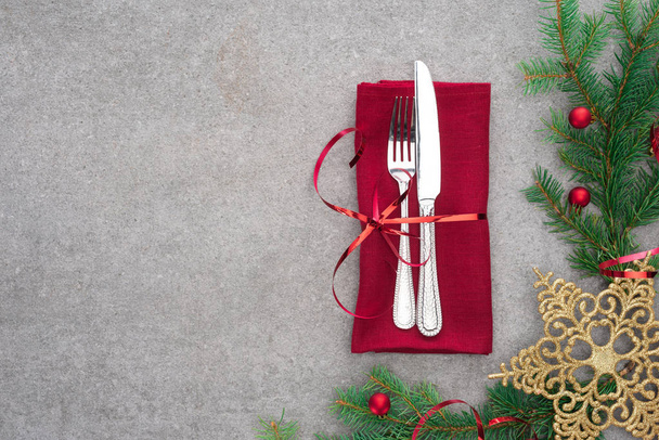 płaskie lay z widelcem i nożem, zapakowane przez czerwoną wstążką na stole z zimozielonych oddział zdobione bombki i golden star Boże Narodzenie - Zdjęcie, obraz
