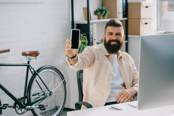 Lächelnder Geschäftsmann zeigt Smartphone vor Kamera - Foto, Bild