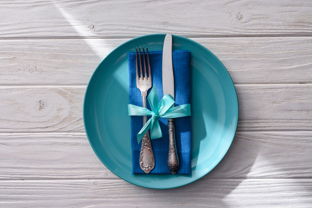 flat lay with fork and knife wrapped by festive ribbon on plate on wooden table  - Fotoğraf, Görsel