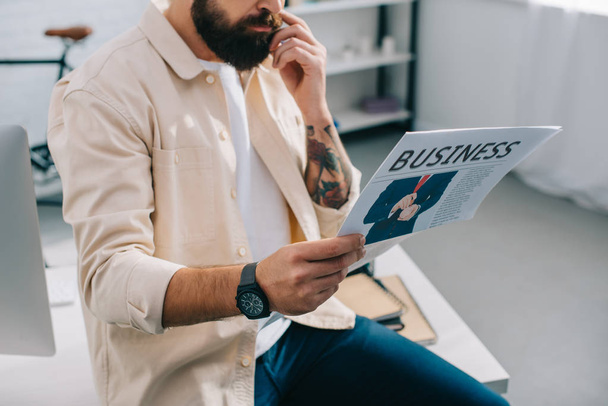 Liikemies istuu ja lukee sanomalehteä modernissa toimistossa
  - Valokuva, kuva