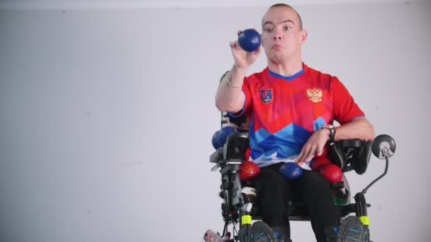 Zdravotně postižený muž na invalidním vozíku. Házení modrý míček ve vzduchu. - Záběry, video