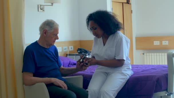 Krankenschwester kümmert sich um älteren männlichen Patienten  - Filmmaterial, Video