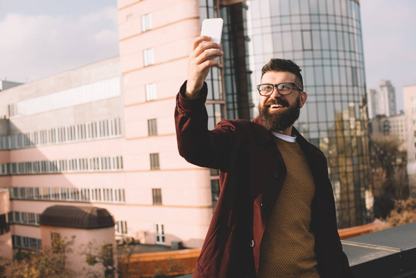 smiling adult man taking selfie on rooftop with beautiful view - Foto, Imagem