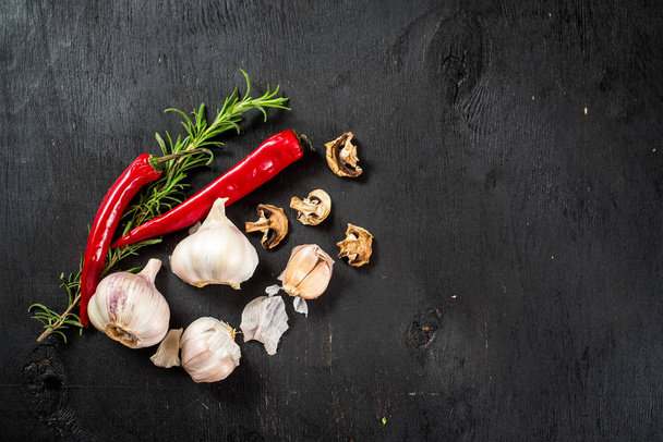 Pepper, garlic, and dry mushrooms flatlay on black background. Top view  free space - Fotó, kép
