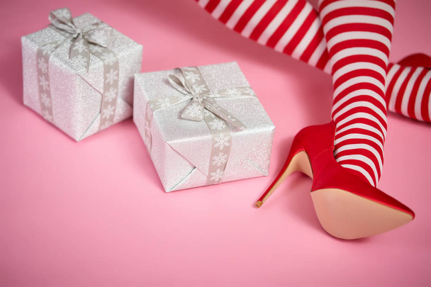 sexy santa woman's legs on a bright pink background and Christmas gifts - Foto, afbeelding