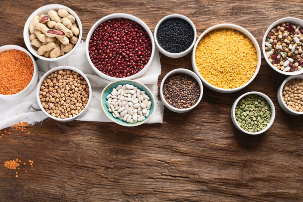 Various dry legumes in bowls on wooden board. - 写真・画像