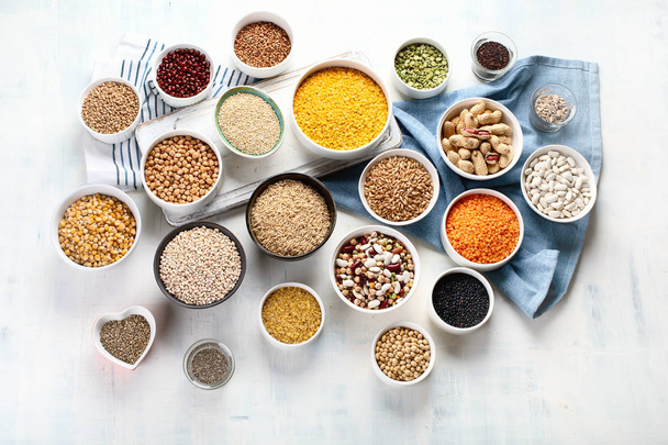 Various grains, cereals, seeds and beans in bowls on table. - Foto, afbeelding