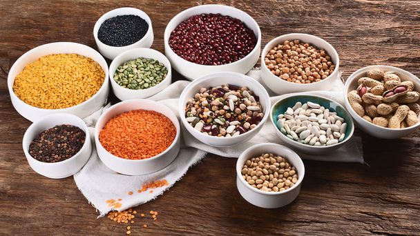 Various dry legumes in bowls on wooden board. - Foto, Imagen