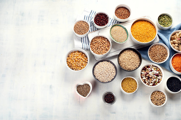 Various grains, cereals, seeds and beans in bowls on table. - Photo, image