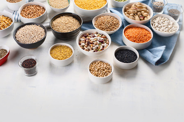 Various grains, cereals, seeds and beans in bowls on table. - Fotoğraf, Görsel