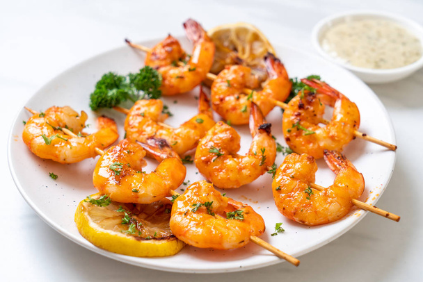 Grilled tiger shrimps skewers with lemon - seafood style - 写真・画像