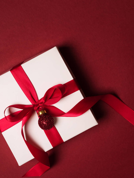 Top view of gift box with red ribbon and glitter ball over red background - Fotoğraf, Görsel