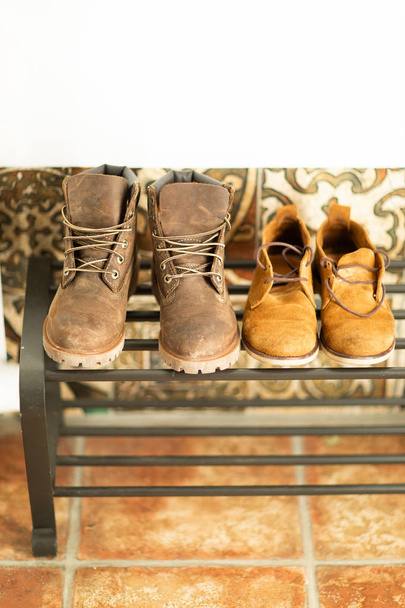 Brown leather autumn boots stand on the shelf in the hallway of the house near the white wall - Zdjęcie, obraz