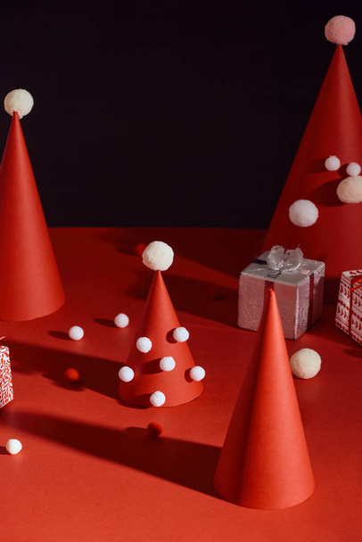Luovat valkoiset ja punaiset joulukuuset, jotka on valmistettu paperista ja lahjapakkauksista mustalla taustalla
 - Valokuva, kuva