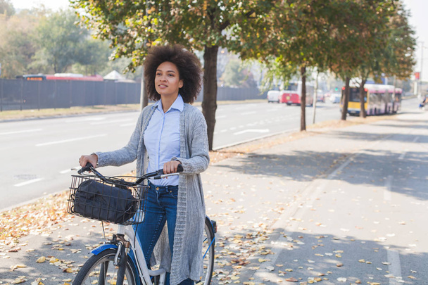 Portrait of pretty Afro woman ride bicycle on street. - Foto, imagen