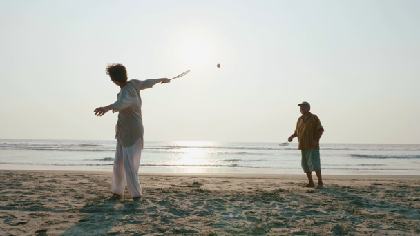 Ενεργό ανώτερος ζευγάρι παίζει μπάλα ballon tai chi στην παραλία. - Πλάνα, βίντεο