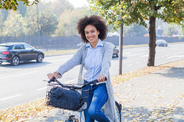 Portrait of happy Afro woman ride bicycle on street. - Fotó, kép