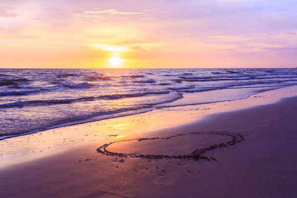 Heart shape drawn on a sandy beach at sunse - Photo, Image