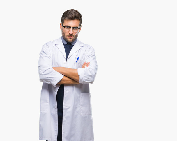 Young handsome man wearing doctor, scientis coat over isolated background skeptic and nervous, disapproving expression on face with crossed arms. Negative person. - Foto, afbeelding