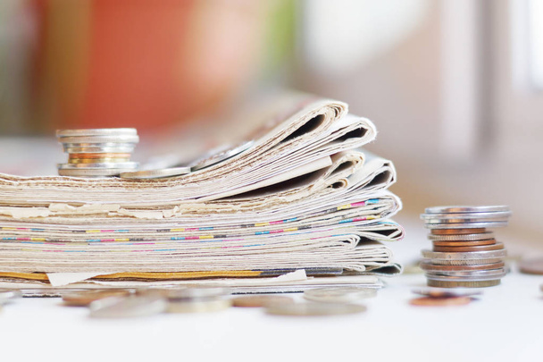 Newspapers. Folded and rolled papers with news ( tabloid journals ) and lots of coins scattered on table, concept for business and communication - Photo, Image