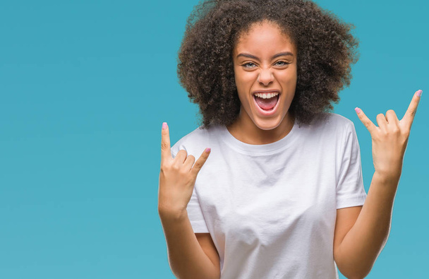 Молодая афро-американка на изолированном фоне кричит с сумасшедшим выражением, делая рок-символ с поднятыми руками. Музыкант. Тяжёлая концепция
. - Фото, изображение