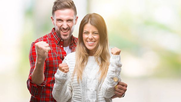Mladý pár v lásce nosit zimní svetr izolované pozadí velmi šťastný a nadšený, dělá vítěze gesto s rukama zvedl, usmíval se a křičí na úspěch. Koncept oslav. - Fotografie, Obrázek