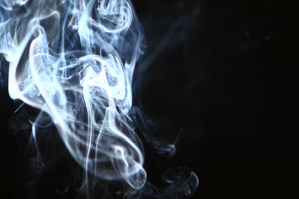 beautiful swirl light bright smoke against heavy black background. - Photo, image