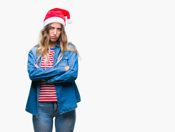 Kaunis nuori blondi nainen yllään joulu hattu yli eristetty tausta skeptinen ja hermostunut, paheksuva ilme kasvot ristissä kädet. Kielteinen henkilö
. - Valokuva, kuva