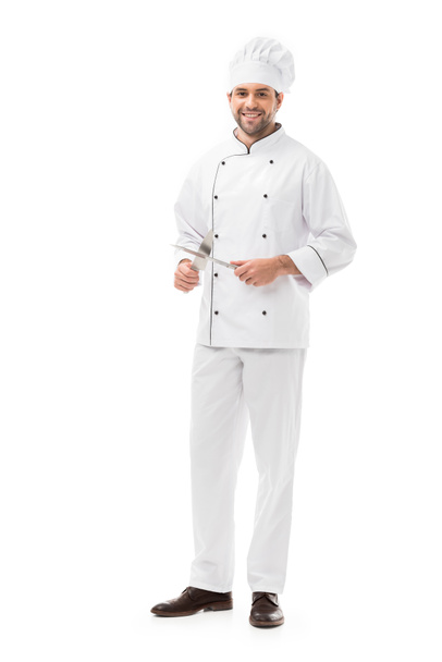 jovem chef feliz segurando facas de corte e olhando para a câmera isolada no branco
 - Foto, Imagem